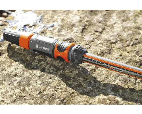 Gardena slangkoppling med vattenslang på en stenbelagd yta