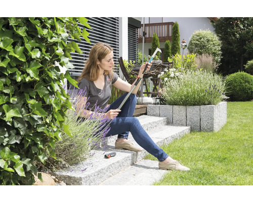 Kvinna sitter i trädgården och inspekterar en fruktplockare