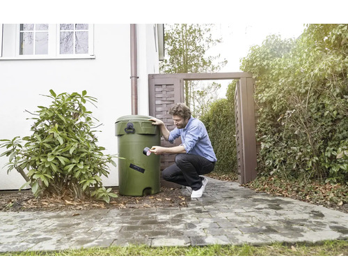 Man reparerar en regnvattentunna med tejp i trädgården.