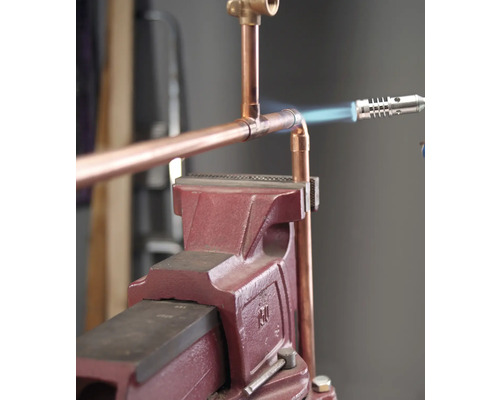 Kopparrör anslutet med en lödkolv och en arbetsbänk