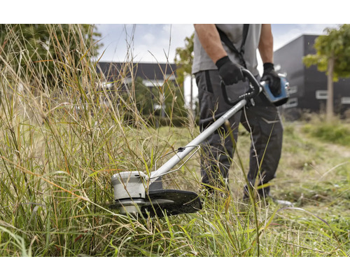 Man klipper gräs med en trimmer.