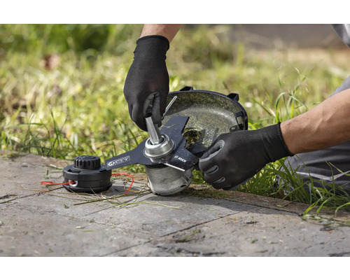 En man byter kniven på en grästrimmer.