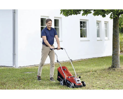 Man klipper gräs med en elektrisk gräsklippare