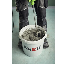 En hantverkare blandar kakelfix i en hink av märket Akkit med en elektrisk mixer.