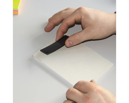 Hand med magnetremsa på vit kartong