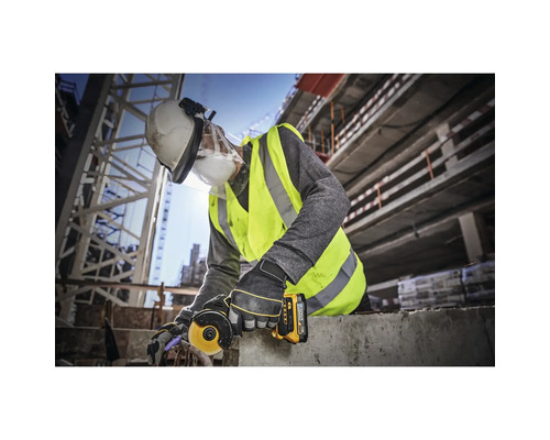 En byggnadsarbetare använder en vinkelslip på en byggarbetsplats och bär skyddskläder.