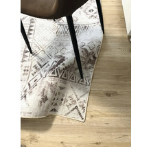 Dekorativ matta med geometriska mönster under en stol på trägolv.