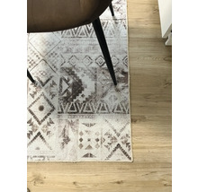 Matta med grafiskt mönster under en stol på trägolv.