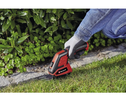 Einhell logotyp. En person använder en batteridriven grässax för att trimma gräsmattans kanter.