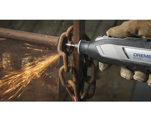 En person använder ett Dremel 8240 multiverktyg för att skära en kedja, vilket skapar gnistor.