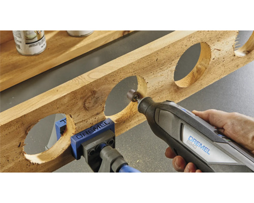 Dremel multifunktionsverktyg som bearbetar en träbit med runda urtag, fastsatt med en skruvtving
