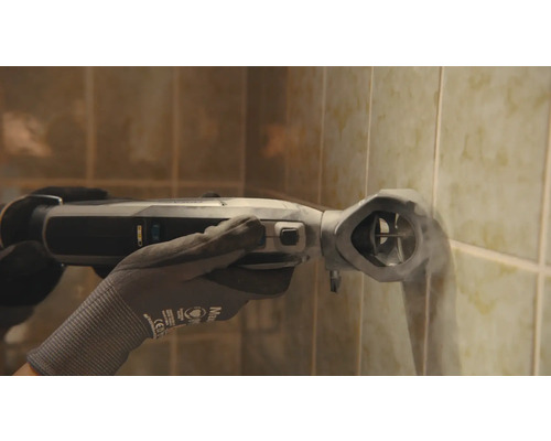 En person använder ett oscillerande elverktyg på en kakelvägg.