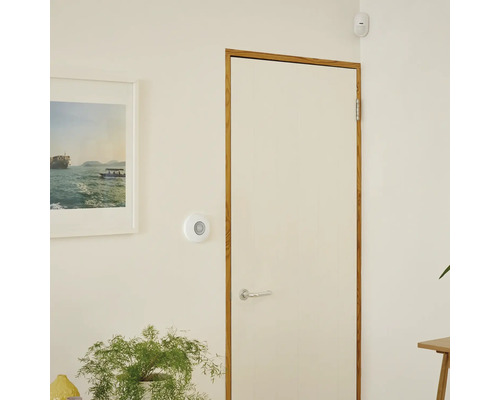 Interiörbild av ett rum med dörr, rörelsesensor och bild