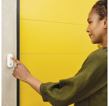 Kvinna trycker på dörrklockan på väggen