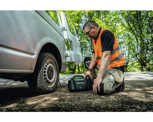 En man fyller ett däck på en skåpbil med en mobil kompressor från Metabo.