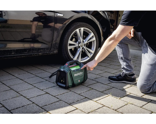 Metabo batterikompressor bredvid en bil på gatstenar
