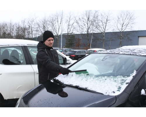 Man tar bort snö från en bilruta med en borste