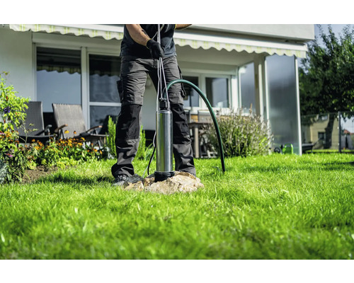 En man installerar en djupbrunnspump i trädgården.