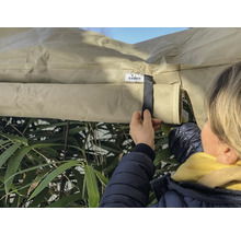 Person fäster ett skyddshölje utomhus med kardborreband