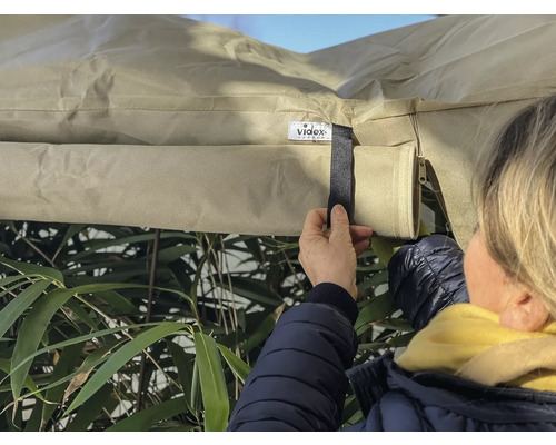 Person fäster ett skyddshölje utomhus med kardborreband