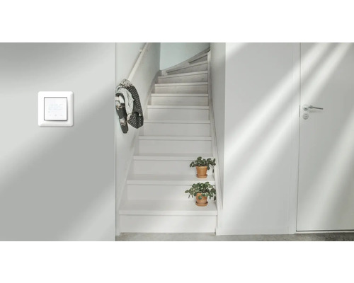 Ljus hall med trappa, värmeregulator och dörr