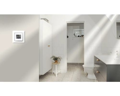 Badrum med digital rumstermostat på väggen, handfat och skåp