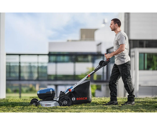 Man använder en sladdlös Bosch gräsklippare i trädgården.