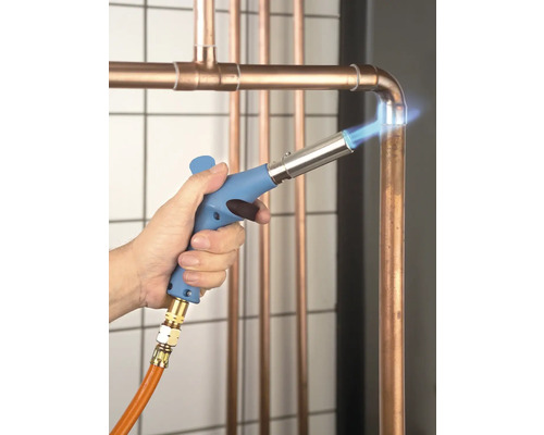 En hantverkare löder kopparrör med en lödanordning.