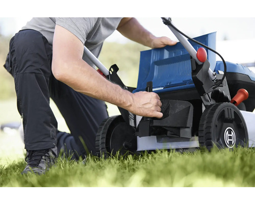 En person förbereder en gräsklippare för trädgårdsarbete