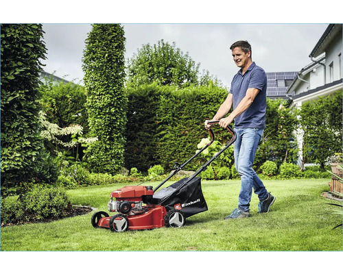 Man klipper gräsmattan med en Einhell gräsklippare i trädgården.