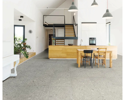 Ljust vardagsrum med grått klinkergolv, köksbord och trappa