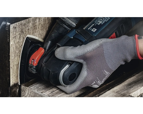 En hand med arbetshandske använder ett elverktyg för att slipa trä.