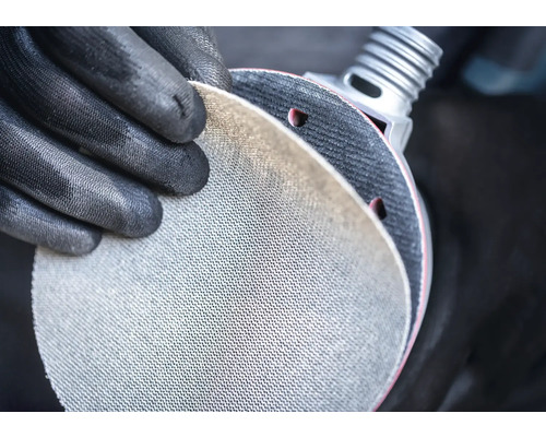 Person med skyddshandskar håller slipskiva