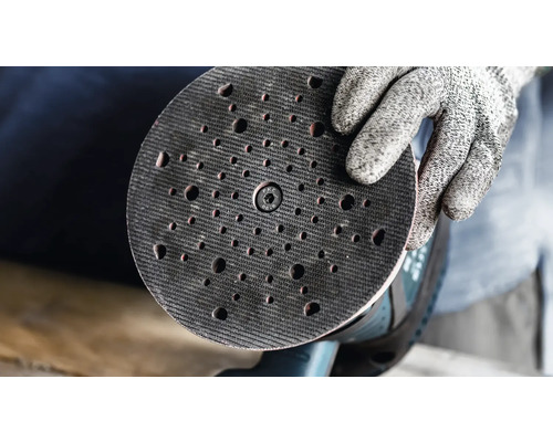 En sliprondell för en excenterslip hålls av en hand med en skyddshandske.