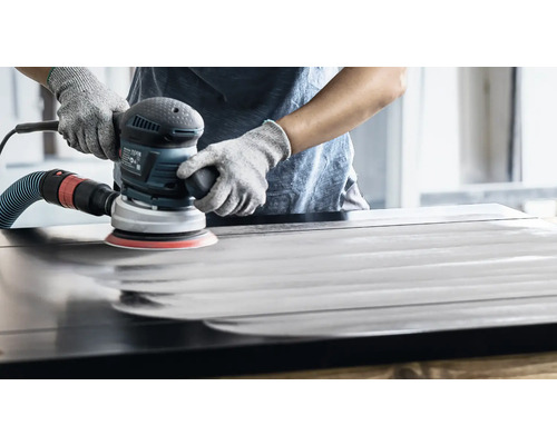 En person slipar en träyta med en excenterslipmaskin.