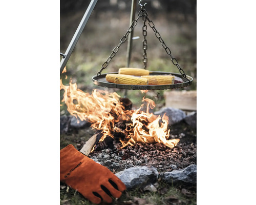 Grill med majskolvar över öppen eld och grillhandske