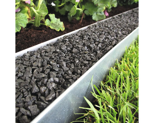 Trädgård med gräsmatta, växter och rabattkant av metall fylld med dekorativt grus