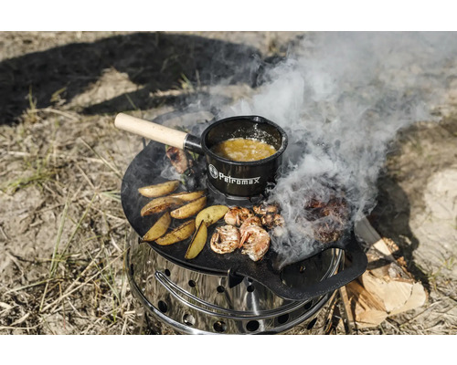 En Petromax Atago-grill med grillplatta, mat på den och en Petromax-kastrull