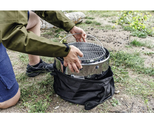 Person som monterar bärbar grill på en äng