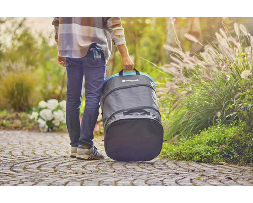 En person bär en Gardena trädgårdssäck i trädgården.