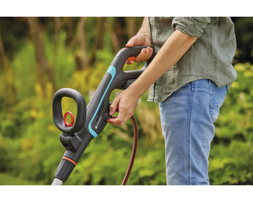 Person använder Gardena grästrimmer i trädgården