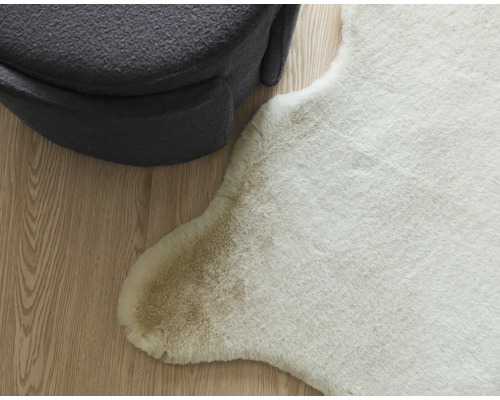 Dekorativ imitation av djurhud bredvid en grå sittpuff på ett trägolv.