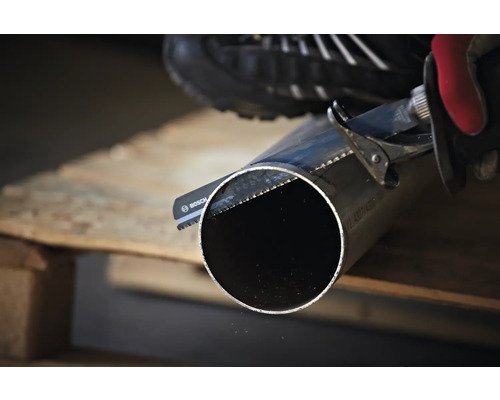 En person sågar ett rör med en tigersåg.