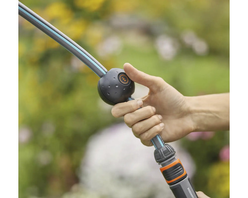 En person håller en trädgårdsslang med vattenstoppfunktion.