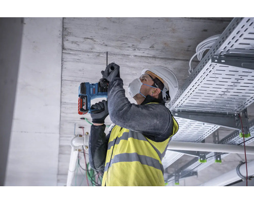 Hantverkare borrar ett hål i taket med en borrhammare.