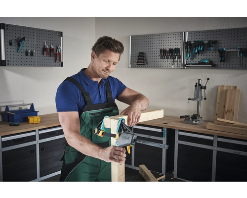 Man fäster trä med en skruvtving i en verkstad.