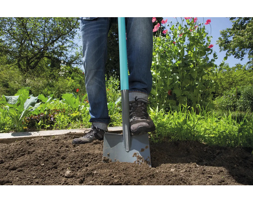 Person sticker spade i trädgårdsjord