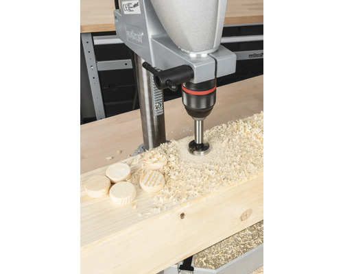 Borrmaskin borrar hål i träbräda, med träspån och träskivor