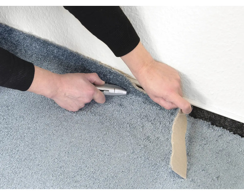 Skära en matta med en skärmkniv längs en vägg