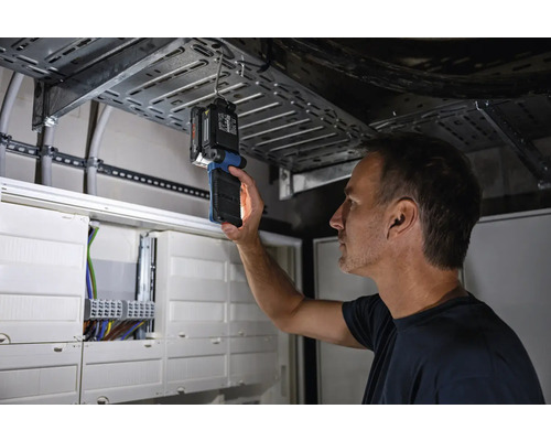 En man inspekterar en elektrisk installation med en inspektionslampa.